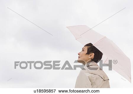 Woman wearing raincoat and holding umbrella View Large Photo Image Stock Photo - Woman wearing raincoat and holding umbrella. Fotosearch