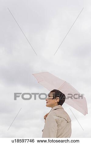 Woman wearing raincoat and holding umbrella View Large Photo Image Stock Photograph - Woman wearing raincoat and holding umbrella. Fotosearch