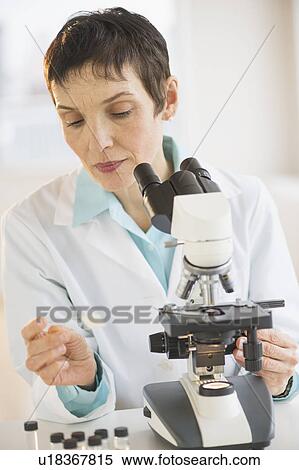 Stock Photography - Woman working with microscope in laboratory. Fotosearch