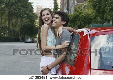 Young couple embracing standing by car View Large Photo Image Stock Image - Young couple embracing standing by car. Fotosearch