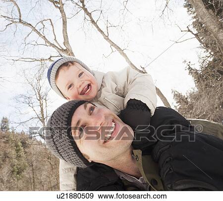 Stock Photo - Young man carrying his son (12-17 months) on shoulders. Fotosearch
