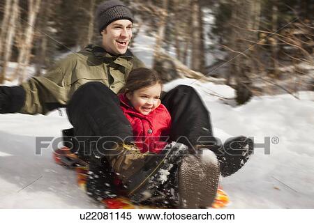 Stock Photography - Young man sledding with girl (2-3). Fotosearch