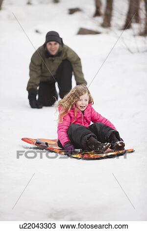 Stock Image - Young man sledding with girl (4-5). Fotosearch