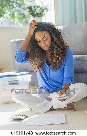 Stock Image - Young woman dealing with home finance. Fotosearch