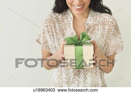 Stock Image - Young woman holding present. Fotosearch