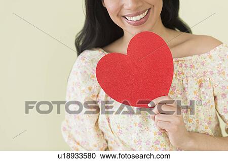 Stock Image - Young woman holding red paper heart. Fotosearch