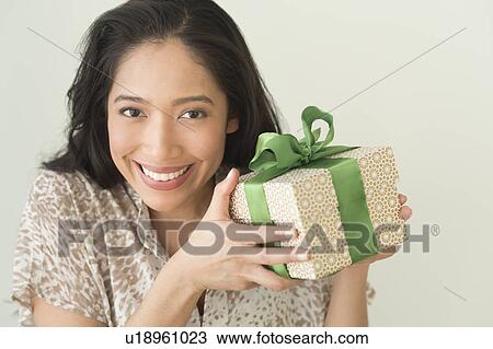 Stock Image - Young woman holding wrapped gift. Fotosearch