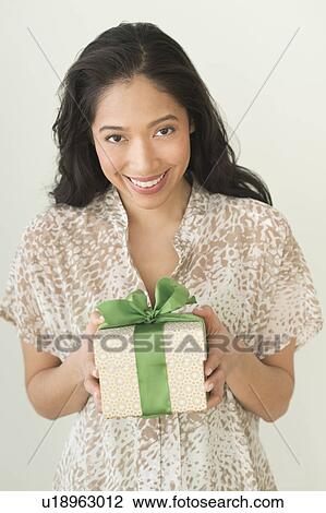 Stock Image - Young woman holding wrapped gift. Fotosearch