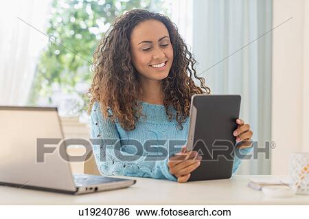 Stock Photograph - Young woman in home office. Fotosearch