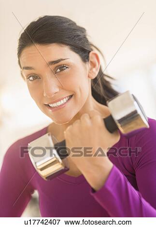 Stock Photo - Young woman lifting dumbbell. Fotosearch