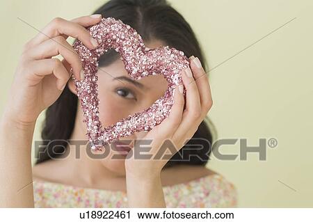 Stock Image - Young woman looking through glittering heart. Fotosearch