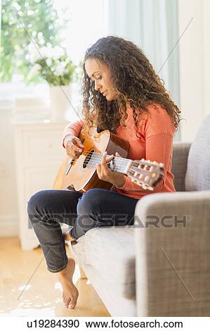 Stock Image - Young woman playing guitar. Fotosearch