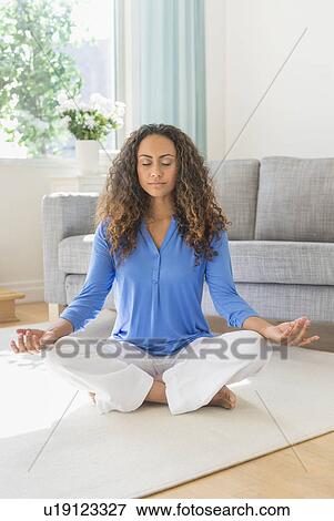 Young woman practicing yoga in living room View Large Photo Image Stock Photo - Young woman practicing yoga in living room. Fotosearch