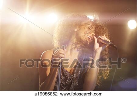 Young woman singing in spotlight View Large Photo Image Stock Image - Young woman singing in spotlight. Fotosearch