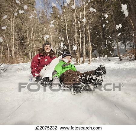Stock Image - Young woman sledding with boy (4-5). Fotosearch
