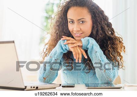 Picture - Young woman using laptop at home office. Fotosearch