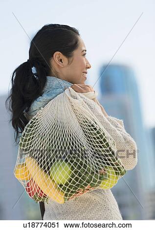 Stock Image - Young woman with grocery shopping bag. Fotosearch
