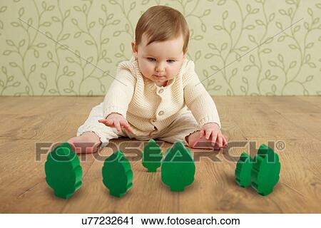 Stock Image - Baby girl with toy trees. Fotosearch