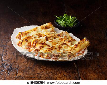 Picture - Beef Cannelloni on white platter with rocket salad. Fotosearch