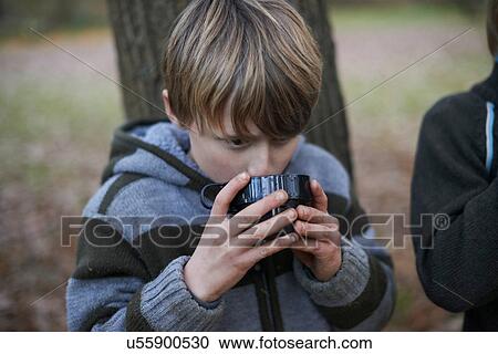 Stock Image - Boy drinking hot drink in forest. Fotosearch