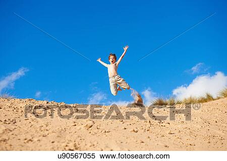 Stock Photography - Boy jumping on beach. Fotosearch