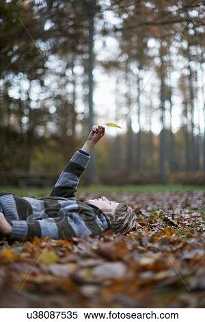 Boy lying on forest floor holding leaf in air View Large Photo Image Stock Photography - Boy lying on forest floor holding leaf in air. Fotosearch
