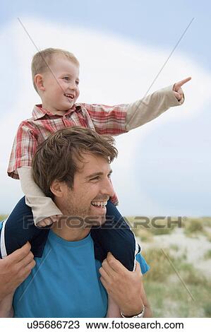Stock Image - Boy on father's shoulders, pointing. Fotosearch