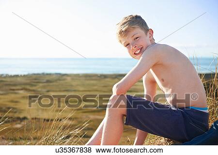 Stock Photo - Boy sitting on beach. Fotosearch
