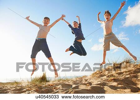 Boys and teenage girl jumping on beach View Large Photo Image Stock Image - Boys and teenage girl jumping on beach. Fotosearch