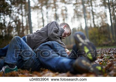 Picture - Boys play fighting on forest floor. Fotosearch