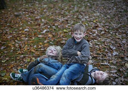 Picture - Boys play fighting on forest floor. Fotosearch