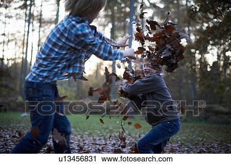 Stock Image - Boys throwing leaves at eachother. Fotosearch