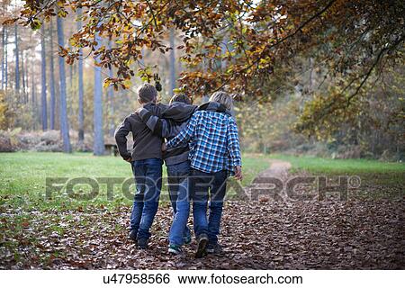 Stock Photograph - Boys walking through forest with arms around eachother. Fotosearch