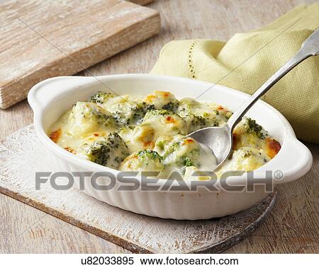 Stock Photography - Broccoli baked in cheese sauce on wooden board. Fotosearch