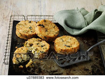 Stock Image - Bubble and squeak cakes on baking sheet with wire rack. Fotosearch