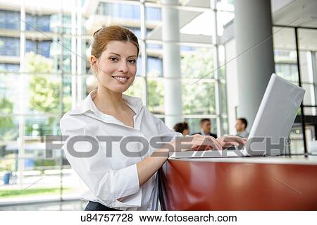Business woman using laptop on reception desk View Large Photo Image Stock Photo - Business woman using laptop on reception desk. Fotosearch
