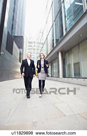 Businessman and businesswoman walking past office buildings View Large Photo Image Stock Photo - Businessman and businesswoman walking past office buildings. Fotosearch