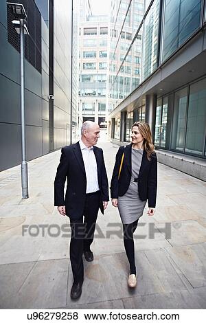 Stock Photo - Businessman and businesswoman walking past office buildings. Fotosearch