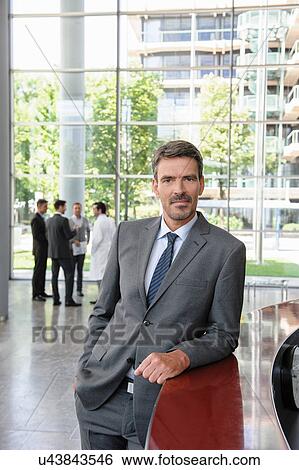 Businessman leaning against reception desk View Large Photo Image Stock Photograph - Businessman leaning against reception desk. Fotosearch
