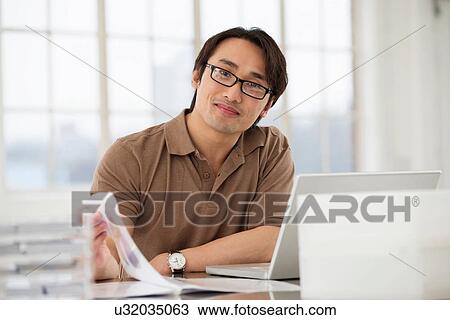 Businessman sitting at desk working View Large Photo Image Stock Image - Businessman sitting at desk working. Fotosearch
