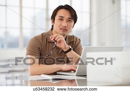 Businessman sitting at desk working View Large Photo Image Stock Image - Businessman sitting at desk working. Fotosearch