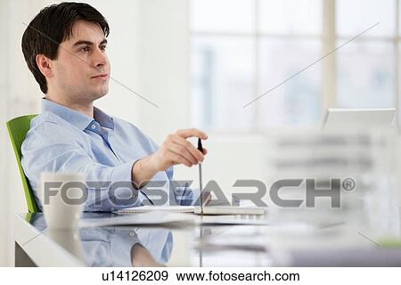 Businessman sitting at desk working View Large Photo Image Stock Photo - Businessman sitting at desk working. Fotosearch
