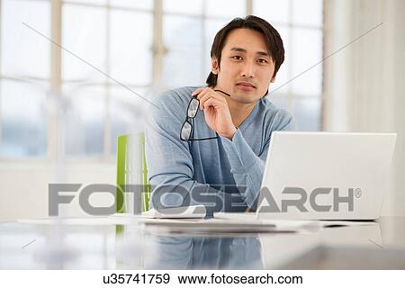 Businessman sitting at desk working View Large Photo Image Stock Photo - Businessman sitting at desk working. Fotosearch