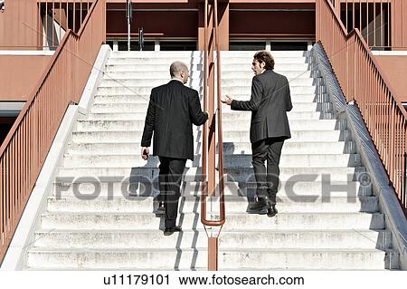 Stock Image - Businessmen ascending staircase, outdoors. Fotosearch