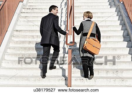 Stock Photo - Businesswoman and man ascending staircase, outdoors. Fotosearch