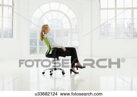 Businesswoman sitting on office chair in sparse white room View Large Photo Image Picture - Businesswoman sitting on office chair in sparse white room. Fotosearch