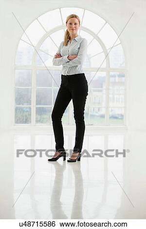 Businesswoman standing in sparse white room View Large Photo Image Stock Photograph - Businesswoman standing in sparse white room. Fotosearch