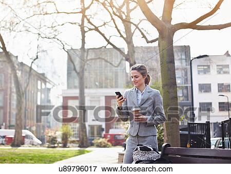 Businesswoman using cell phone in park with coffee View Large Photo Image Stock Photo - Businesswoman using cell phone in park with coffee. Fotosearch