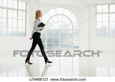 Businesswoman walking in sparse white room View Large Photo Image Stock Image - Businesswoman walking in sparse white room. Fotosearch