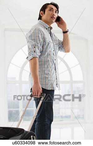 Casual businessman with suitcase on cell phone View Large Photo Image Stock Photo - Casual businessman with suitcase on cell phone. Fotosearch